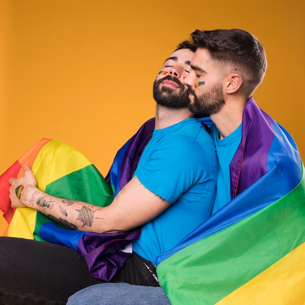 Uomini con la bandiera LGBT che si abbraccia