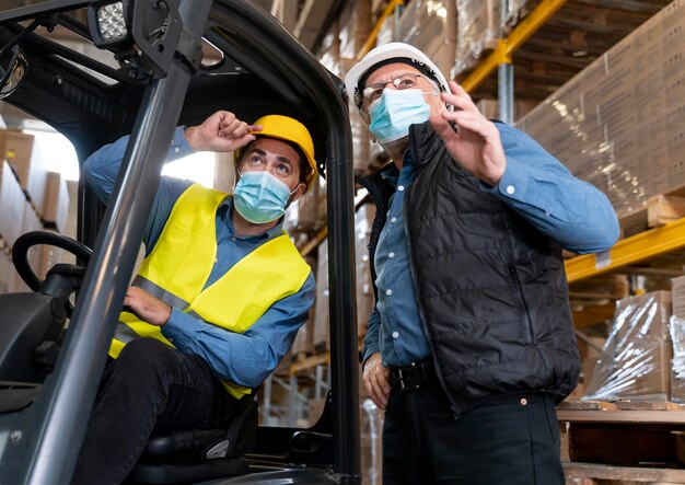 Uomini con la maschera che lavorano in magazzino