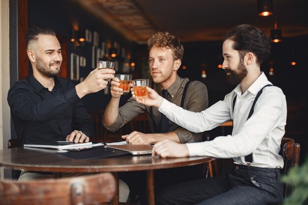 Uomini d'affari nelle trattative. Uomini con alcol seduti al tavolo. Gli amici stanno parlando.