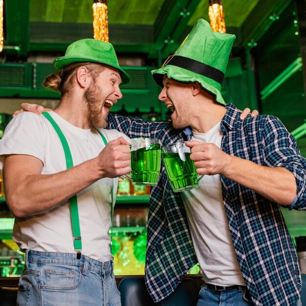 Uomini di smiley che celebrano st. patrick's day al bar con bevande