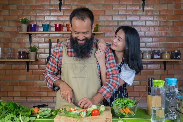 Uomini e donne che cucinano in cucina con muri di mattoni rossi.