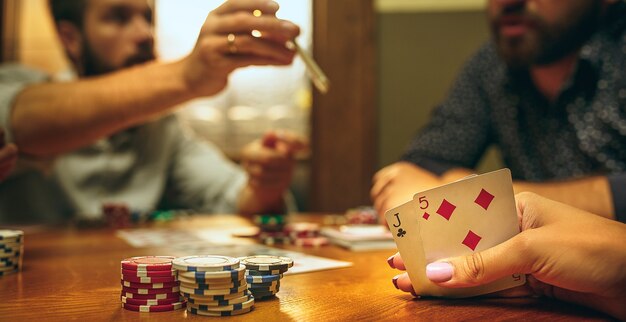 Uomini e donne che giocano a carte. Poker, intrattenimento serale e concetto di eccitazione