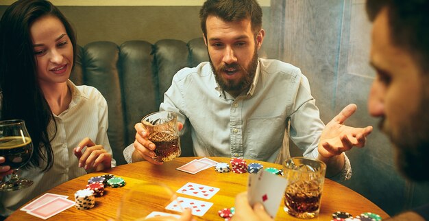 Uomini e donne che giocano a carte. Poker, intrattenimento serale e concetto di eccitazione