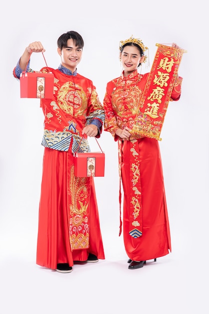 Uomini e donne che indossano cheongsam in piedi, con in mano cartelli di saluto e con borse rosse