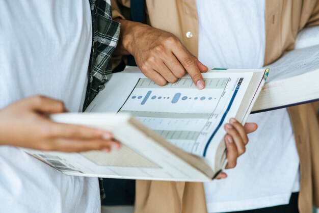 Uomini e donne che indossano maschere stanno e leggono in biblioteca.