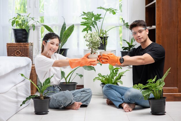 Uomini e donne che indossavano guanti arancioni sedevano e piantavano alberi in una casa.
