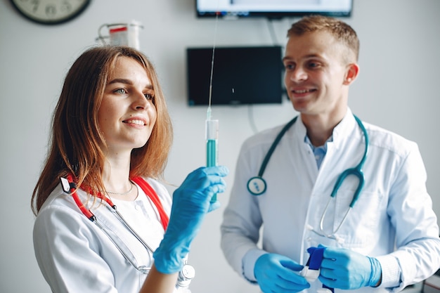 Uomini e donne in camici da ospedale tengono in mano attrezzature mediche. L'infermiera compone il farmaco per l'iniezione.