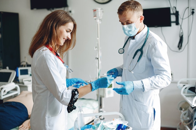 Uomini e donne in camici da ospedale tengono in mano attrezzature mediche. L'infermiera compone il farmaco per l'iniezione.