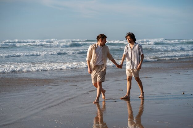 Uomini gay a tutto campo che si tengono per mano in spiaggia