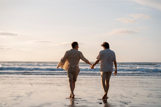 Uomini gay a tutto campo che si tengono per mano in spiaggia