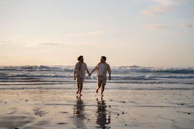 Uomini gay a tutto campo che si tengono per mano in spiaggia