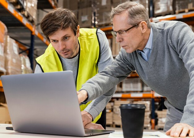 Uomini in magazzino che lavorano al computer portatile