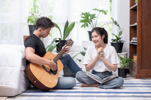 Uomini seduti chitarra e donne in possesso di libri e cantare.