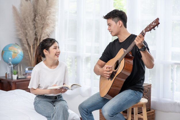 Uomini seduti chitarra e donne in possesso di libri e cantare.