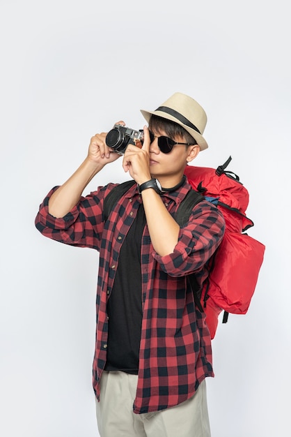 Uomini vestiti per viaggiare, con occhiali e cappelli, con in mano una borsa e una macchina fotografica