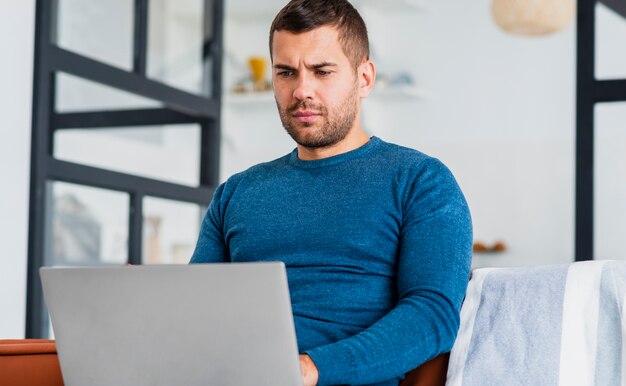 Uomo a casa che lavora al computer portatile