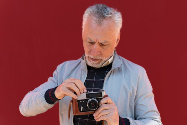 Uomo a colpo medio che tiene in mano una macchina fotografica