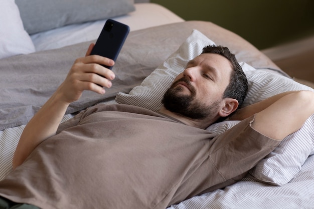 Uomo a letto con smartphone