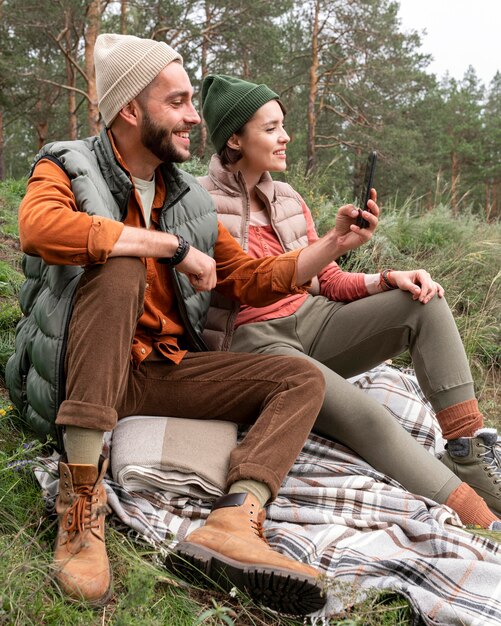 Uomo a metà colpo seduto sull'erba e scattare foto con il telefono vicino alla ragazza