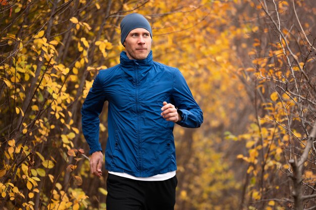 Uomo a metà tiro che corre sul sentiero nella foresta