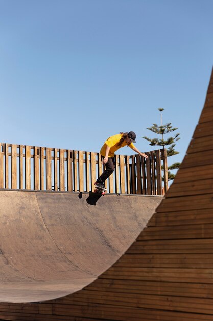 Uomo a tiro lungo che salta sullo skateboard