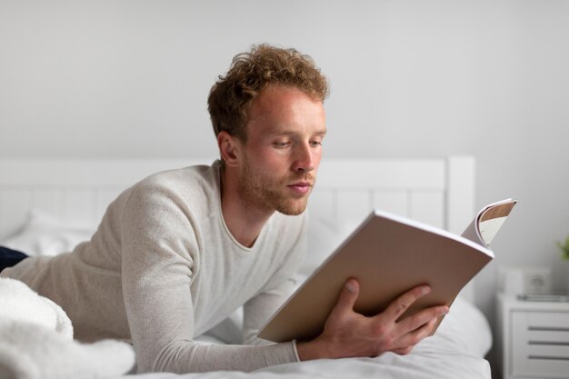 Uomo a tiro medio che legge in camera da letto