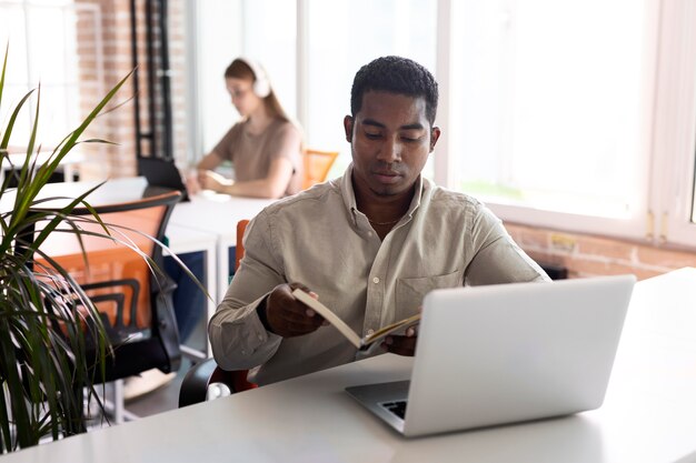 Uomo a tiro medio con laptop e libro