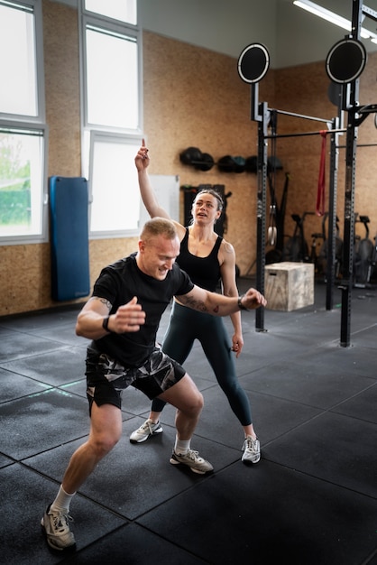 Uomo a tutto campo che fa burpees con l'allenatore