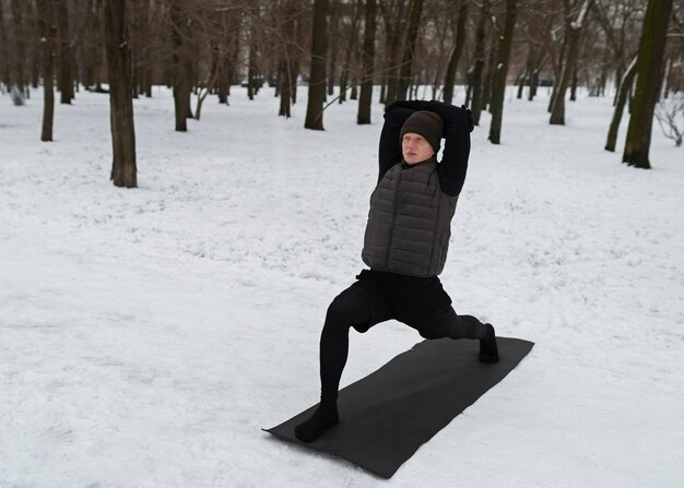 Uomo a tutto campo che fa yoga quando fa freddo