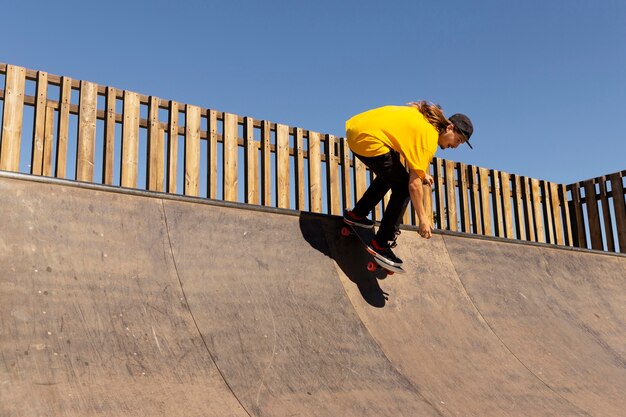 Uomo a tutto campo con lo skateboard che salta