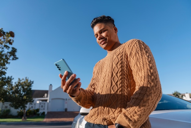 Uomo ad angolo basso che utilizza lo smartphone all'aperto