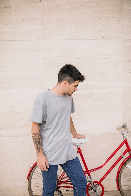 Uomo adolescente guardando la sua bicicletta appoggiata sul muro