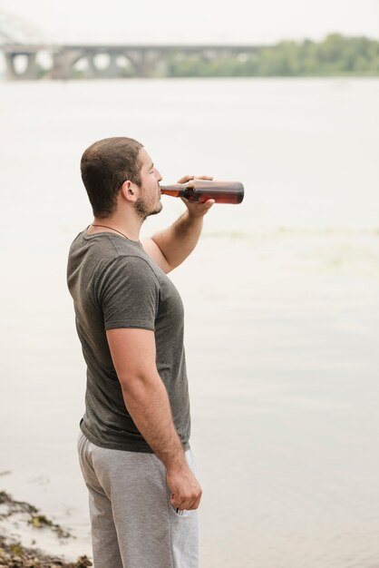 Uomo adulto che gode della birra vicino al fiume