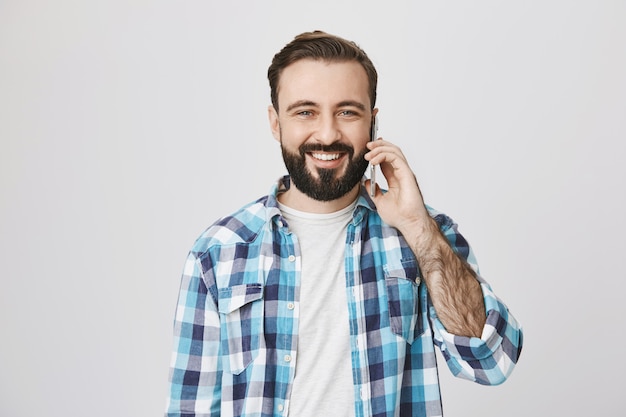 Uomo adulto sorridente amichevole che parla sul telefono