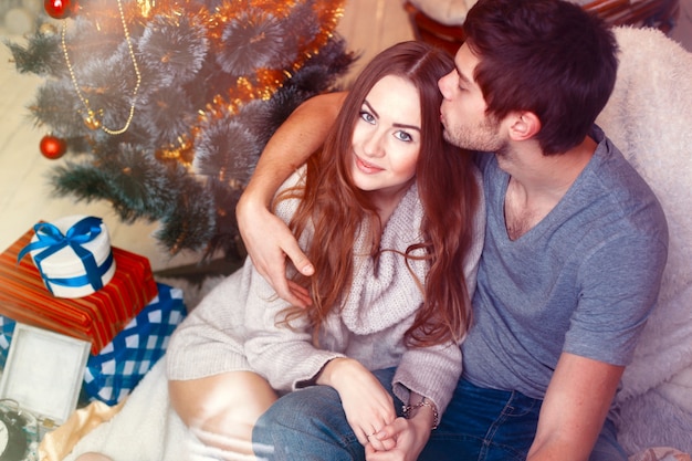 Uomo affettuoso baciare la testa di sua moglie accanto l&#39;albero di Natale