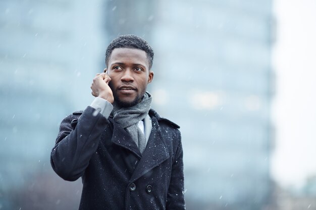 Uomo africano bello sul telefono in via