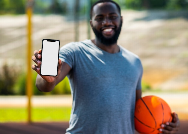 Uomo africano di pallacanestro che mostra il suo telefono