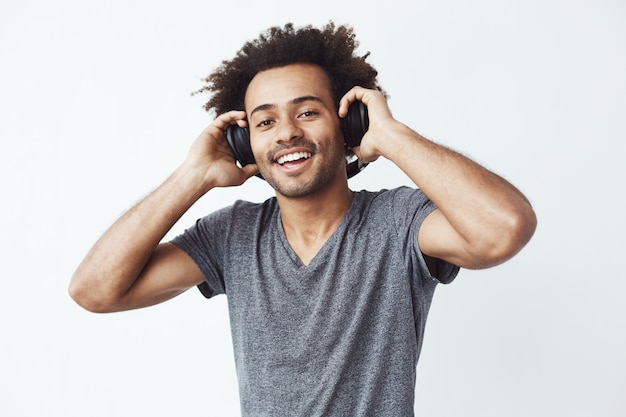 Uomo africano felice che sorride ascoltando la musica in cuffia.