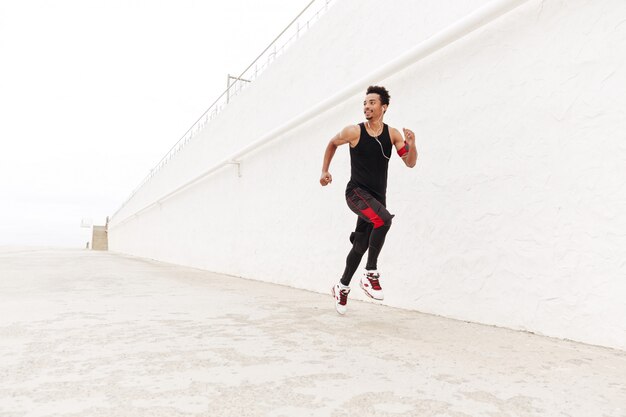 Uomo africano felice di sport che corre all'aperto.