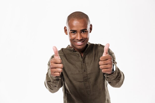 Uomo africano sorridente che mostra i pollici su e lo sguardo