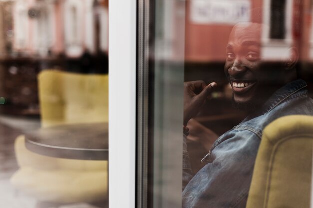Uomo afroamericano adorabile che sorride attraverso la finestra