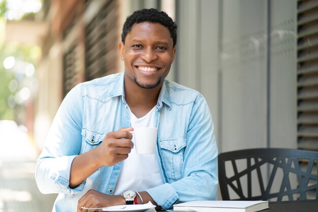 Uomo afroamericano che gode e beve un caffè mentre era seduto al bar all'aperto