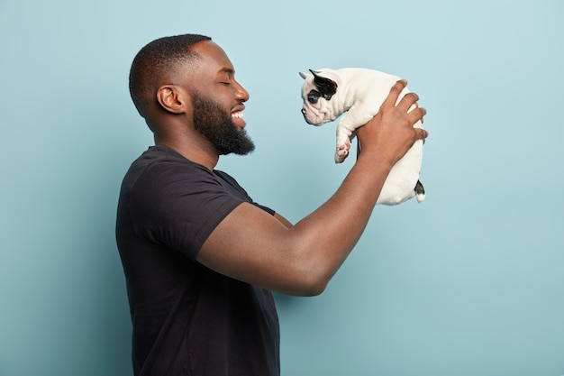 Uomo afroamericano che indossa la maglietta nera e che tiene piccolo cane