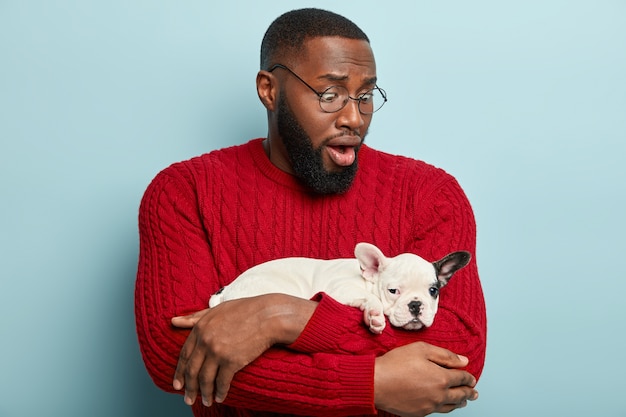 Uomo afroamericano che indossa un maglione rosso e che tiene piccolo cane