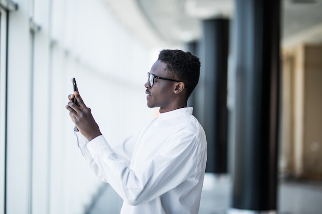 Uomo afroamericano che parla selfie con Smartphone che prende le foto in ufficio