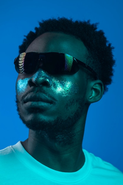 Uomo afroamericano con la pittura del viso indossando occhiali da sole