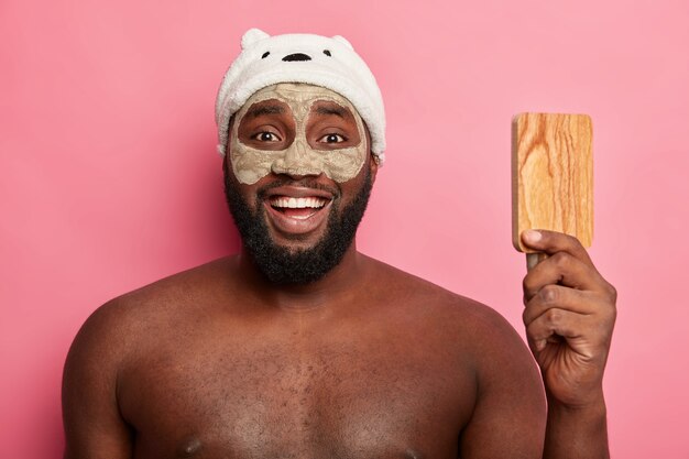 Uomo afroamericano con maschera all'argilla, esprime emozioni positive isolate
