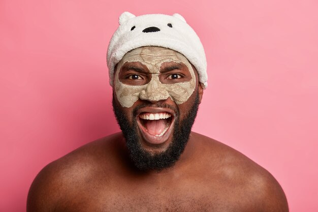 Uomo afroamericano con maschera all'argilla, esprime emozioni positive isolate