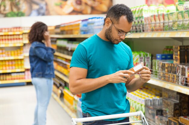 Uomo afroamericano concentrato che legge informazioni sull'imballaggio