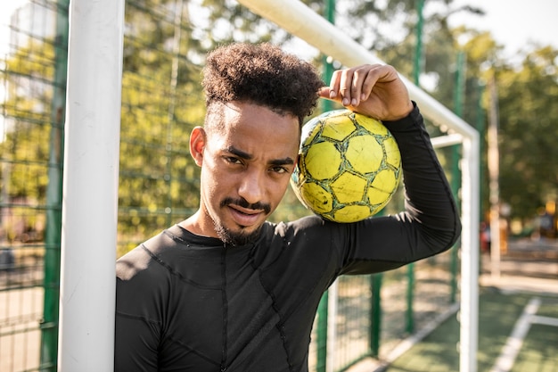 Uomo afroamericano in posa con un pallone da calcio su un campo